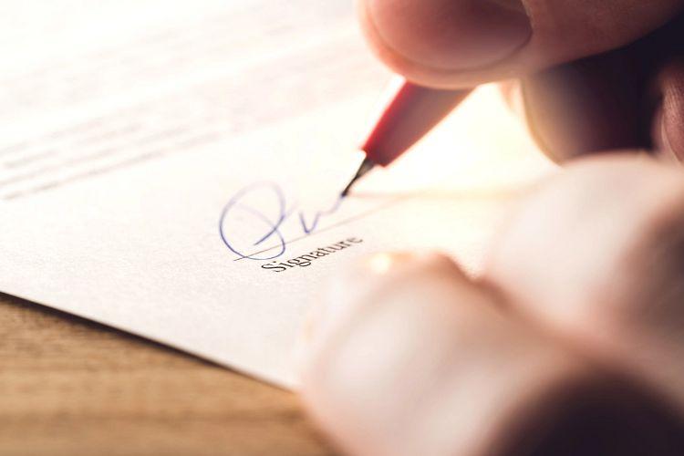 Man writing signature with pen on paper. Settlement for acquisition, business deal, bank loan or rental apartment. Signing contract, agreement, car lease or legal document. The signature is made up. (Getty Images/iStockphoto)